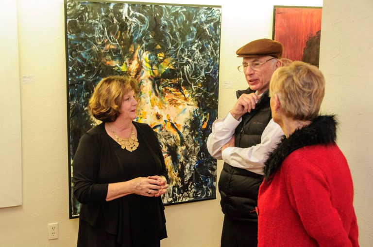 Jesi Pace-Berkeley (in black) standing in front of one of her works at Glenn Eure's Ghost Fleet Gallery.