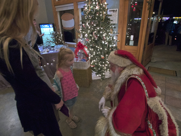 Santa greeting a young lady as she enters Zen Pops during Frostivus.