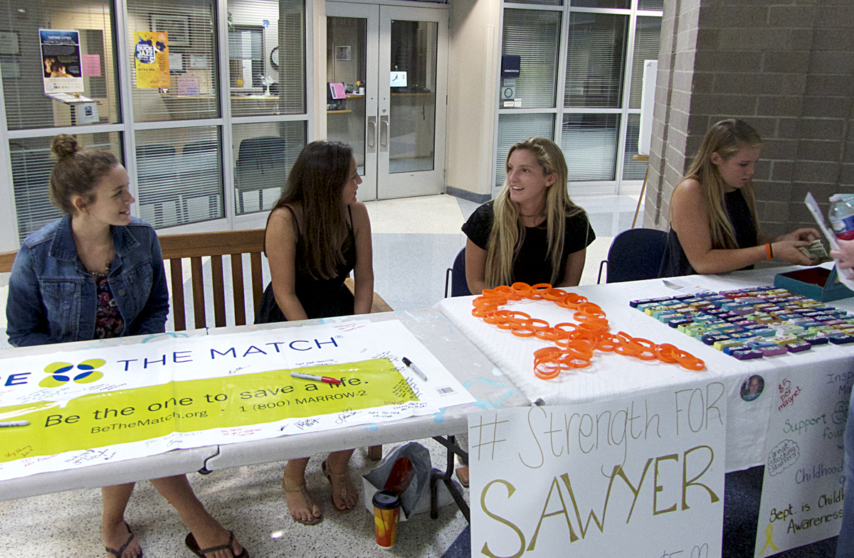 Helping to pay for treatment and research. First Flight High School students man Sawyer's support table.