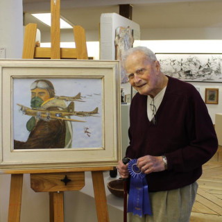 Don Bryan with prize winning painting, Raid on Regensburg, at Ghost Fleet Gallery's self-portrait show in April.
